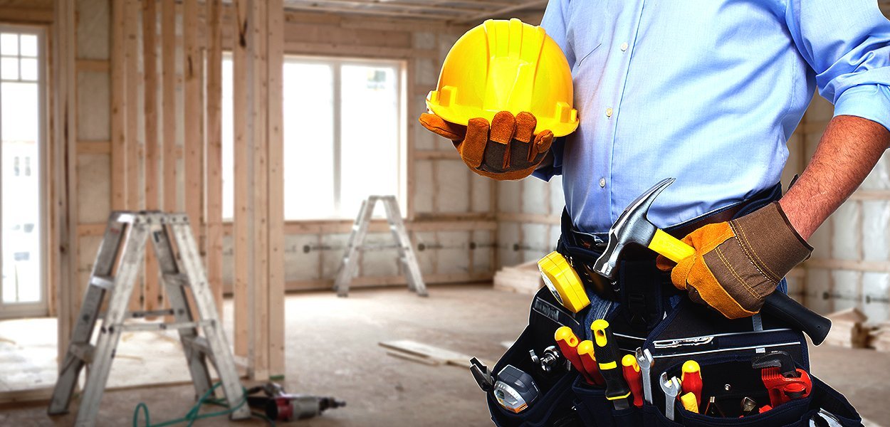 Contractor with tool belt and hard hat at a construction site