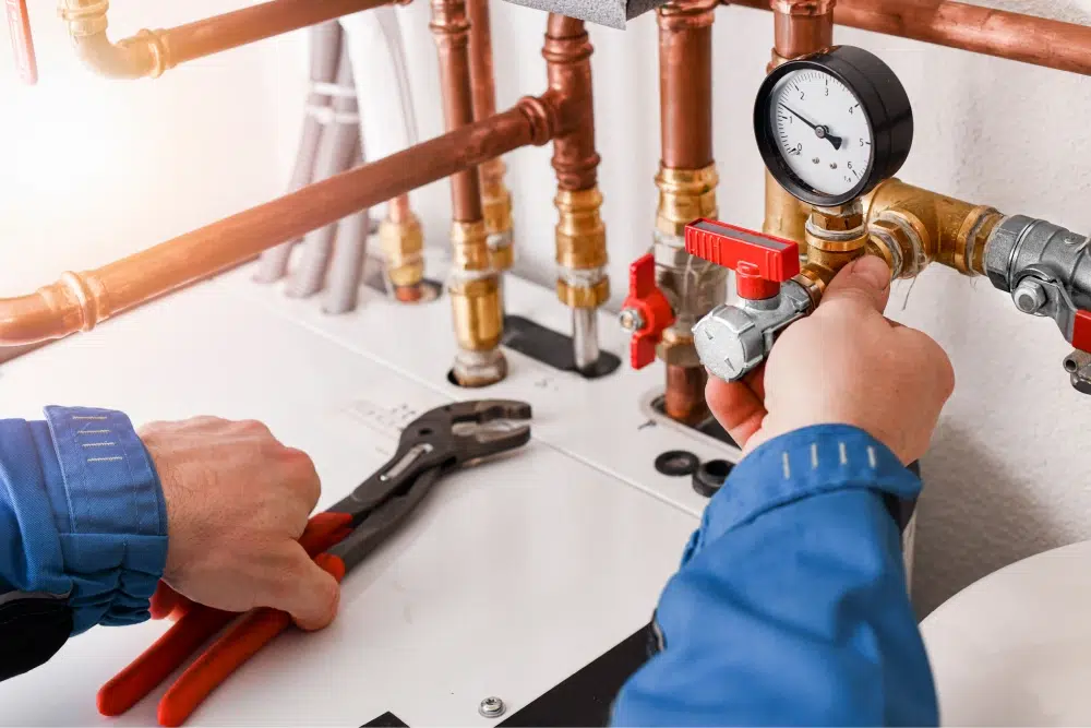Plumber repairing copper pipes and valves with a wrench